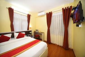 Habitación de hotel con cama y TV en Hotel Odyssey Nepal, en Katmandú