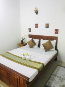 Schlafzimmer mit einem Bett mit weißer Bettwäsche und Kissen in der Unterkunft The wild culture in Sigiriya