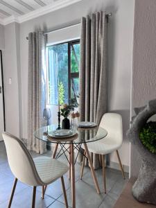 een eetkamer met een tafel en stoelen en een raam bij La Creme Ilanga Waterkloof in Pretoria