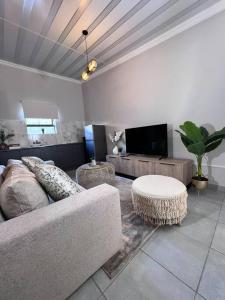 a living room with a couch and a tv at La Creme Ilanga Waterkloof in Pretoria