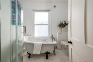 La salle de bains blanche est pourvue d'une baignoire et de toilettes. dans l'établissement 5 bed Central Cambridge House, à Cambridge