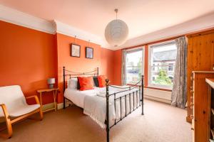 a bedroom with orange walls and a bed and a chair at 5 bed Central Cambridge House in Cambridge