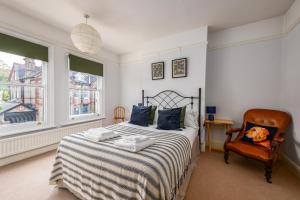 a bedroom with a bed and a chair and two windows at 5 bed Central Cambridge House in Cambridge
