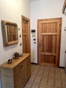 baño con lavabo, espejo y puerta en Cozy Mountain Apartment with Cimone view, en Faidello