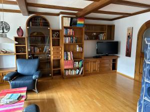 a living room with a tv and book shelves at Traumhaft große Ferienwohnung nähe Attersee in Sankt Georgen im Attergau +40 photos