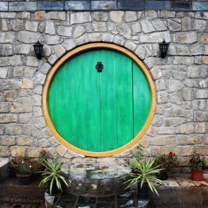 una puerta verde en una pared de piedra con macetas en Hobbit House Bir, en Bīr