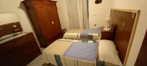Cette chambre comprend 2 lits et une armoire en bois. dans l'établissement Casa Bia Mara IUN SU172600, à Villanovaforru