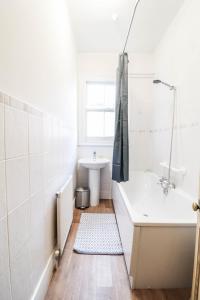 a white bathroom with a tub and a sink at STUNNING 5 bed House in Clapham - FREE WIFI! in London