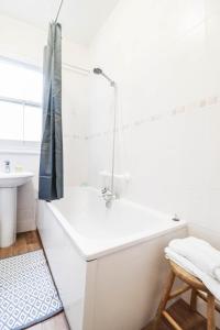 a white bathroom with a bath tub and a stool at STUNNING 5 bed House in Clapham - FREE WIFI! in London