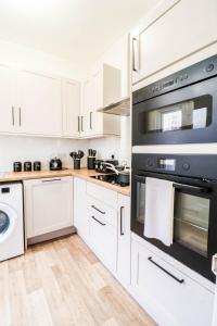 a kitchen with white cabinets and black appliances at STUNNING 5 bed House in Clapham - FREE WIFI! in London