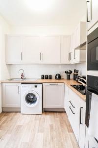 a kitchen with white cabinets and a washing machine at STUNNING 5 bed House in Clapham - FREE WIFI! in London