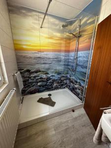 uma casa de banho com um chuveiro e uma pintura do oceano em Hotel Garni Nolting em Esens