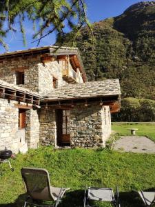 a stone house with chairs in front of it at Chalet la Tuilière***** in Bonneval-sur-Arc