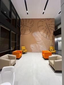 an office lobby with orange chairs and a wall with a mural at PRESIDENCY AIRPORT HOTEL in Cochin