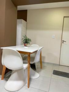 - une table avec des chaises blanches et une plante en pot dans l'établissement APART CONFORT -Excelente Ubicacion y calidad, à Corrientes