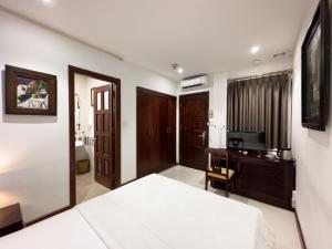 Hoang Yen Hotel - Phu My Hung في مدينة هوشي منه: غرفة نوم بسرير ومكتب وتلفزيون