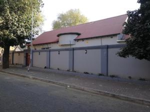 a white building with a red roof on a street at Defountain Guest House in Johannesburg