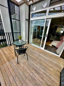 a wooden deck with a table and a bench on it at Plush 3 bedroom property in Hobsonville in Auckland