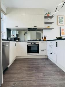 a kitchen with white cabinets and a stove at Plush 3 bedroom property in Hobsonville in Auckland