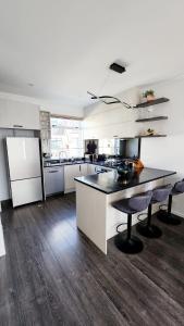 a large kitchen with white cabinets and a black counter top at Plush 3 bedroom property in Hobsonville in Auckland