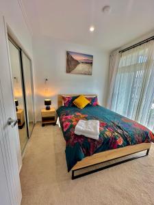 a bedroom with a bed with a colorful comforter at Plush 3 bedroom property in Hobsonville in Auckland
