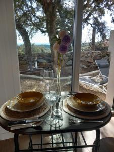 una mesa con platos y vasos y un jarrón con flores en Bungalow Sierra San Vicente, en Hinojosa de San Vicente