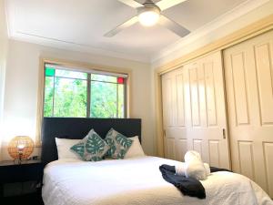 a bedroom with a bed with a ceiling fan at Oasis 5 Bedroom Charming House in Sydney