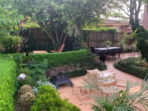 a patio with a table and chairs in a garden at Oasis 5 Bedroom Charming House in Sydney