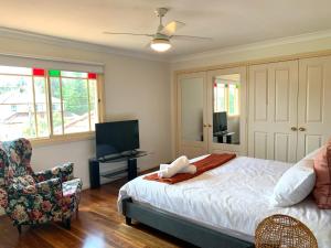 a bedroom with a bed and a chair and a television at Oasis 5 Bedroom Charming House in Sydney
