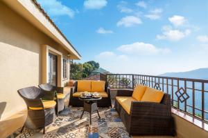 balcón con sofás, mesa y sillas en Courtyard Villa by Hillstaytion,com, en Panchgani