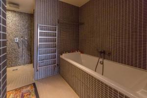 ein Badezimmer mit einer Badewanne und einer gefliesten Wand in der Unterkunft LOFT 11e près Canal St-Martin - Chambre climatisée SDB privée in Paris