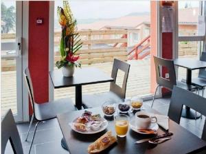 a table with breakfast foods and drinks on it at Hôtel Cantal Cottages in Saint-Georges