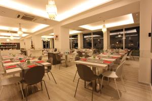 un ristorante con tavoli e sedie bianchi e finestre di Hotel Fantasy a Riccione