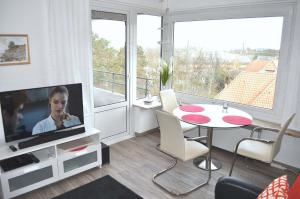 een woonkamer met een televisie en een tafel met stoelen bij Carpe Diem Ferienwohnung Nr 187 Meerblick in Niendorf