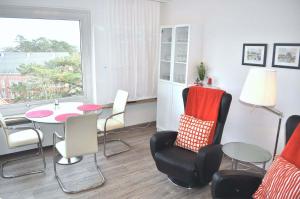 een woonkamer met een tafel en stoelen en een raam bij Carpe Diem Ferienwohnung Nr 187 Meerblick in Niendorf