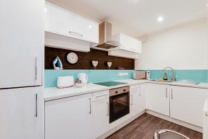 una cocina con armarios blancos y un reloj en la pared en Duke Street Apartment Hotel Liverpool City Centre en Liverpool