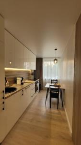 a kitchen with white cabinets and a table in it at Greimo apartamentai in Šiauliai