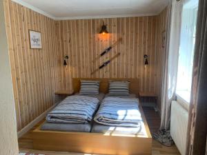 Cama en habitación con pared de madera en Cozy Zweeds huis met openhaard en grote tuin en Ramsele