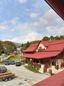 a building with a red roof and a street with cars at Cabana Daianna si Jessica in Poiana Vadului