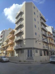 - un grand immeuble avec des voitures garées devant dans l'établissement SinSea Penthouse, à San Pawl il-Baħar