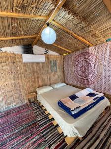 a bed in a wicker room with a rug at Alwaha Camp in Nuweiba