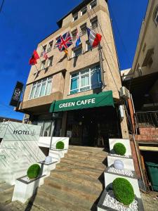 un edificio con un café verde con banderas. en Green Apartments Prishtina, en Pristina