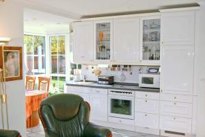 eine Küche mit weißen Schränken und einem grünen Stuhl in der Unterkunft Haus am Kurpark Ferienwohnung Nr 03 in Timmendorfer Strand