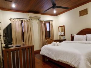a bedroom with two beds and a flat screen tv at somvang khily guesthouse 宋旺吉利 酒店 in Luang Prabang