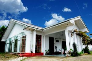 um edifício branco com uma porta vermelha em The West Gate Bungalow em Nuwara Eliya