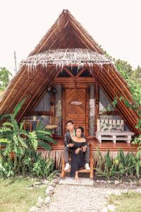 mężczyzna i kobieta siedzący przed domem w obiekcie Tongo Hill Cottages w mieście Moalboal
