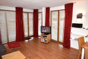 ein Wohnzimmer mit einem TV und roten Vorhängen in der Unterkunft Haus am Strand Ferienwohnung Nr 03 in Häven