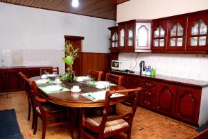 The West Gate Bungalow في نوارا إليا: مطبخ مع طاولة خشبية مع كراسي وكاونتر