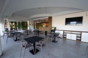 a restaurant with tables and chairs and a flat screen tv at New River Hotel in Borgetto
