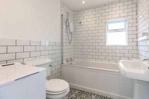 a white bathroom with a toilet and a sink at Peaceful Cottage by the Sea in Norwich +23 photos